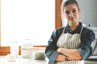 Mutfakta sobanın yanında duran genç bir kadın. .