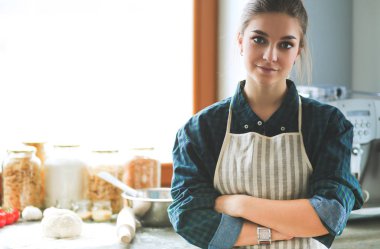 Mutfakta sobanın yanında duran genç bir kadın. .