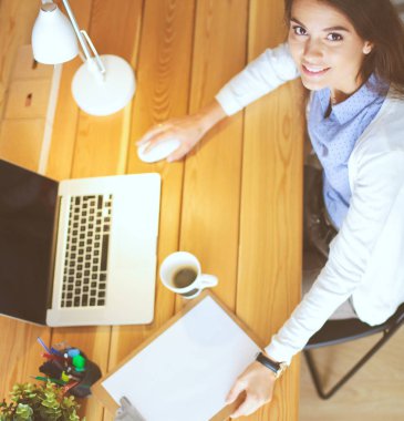 Masasında oturan ve elinde bir fincan kahveyle rahatlamış genç bir kadının portresi. İş kadını. İşyeri