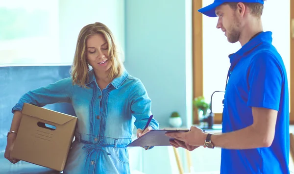 Repartidor sonriente con uniforme azul que entrega la caja de paquetes al destinatario: concepto de servicio de mensajería. Repartidor sonriente en uniforme azul — Foto de Stock