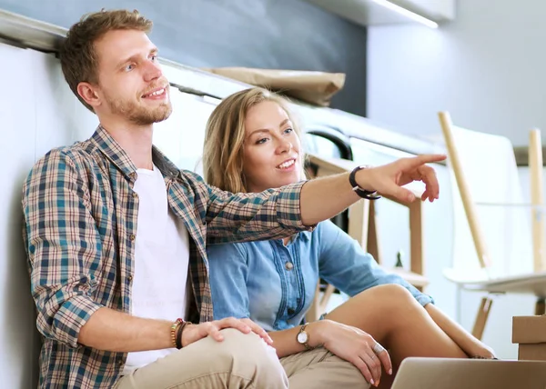 Casal jovem se movendo em nova casa.Sentado e relaxante depois de desempacotar.Olhando algo no laptop. Casal jovem — Fotografia de Stock