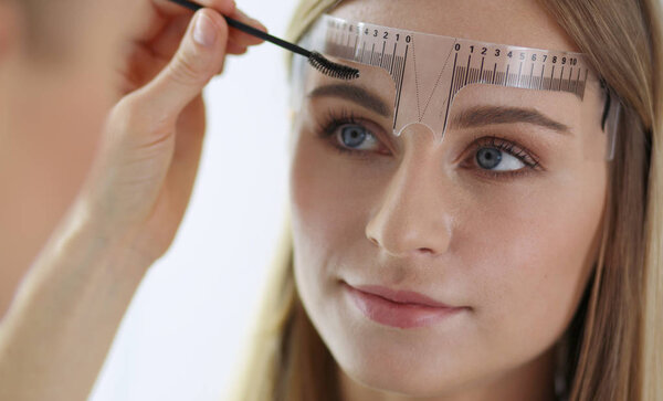 Permanent makeup for eyebrows. Closeup of beautiful woman with thick brows in beauty salon