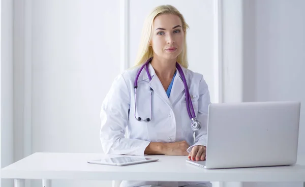 Female doctor sitting on the desk and working a laptop in hospital — Stock Photo, Image