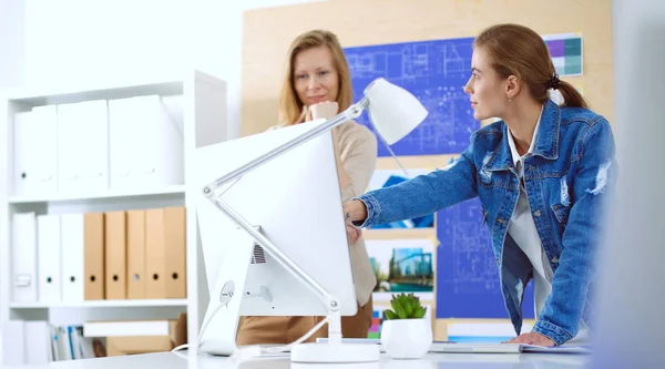 Zwei junge Frauen stehen neben Schreibtisch mit Instrumenten, Plan und Laptop. — Stockfoto