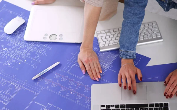 Two young woman standing near desk with instruments, plan and laptop. — Stock Photo, Image