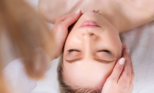 Mujer joven acostada en una mesa de masaje, relajándose con los ojos cerrados. Una mujer. Salón de spa — Foto de Stock