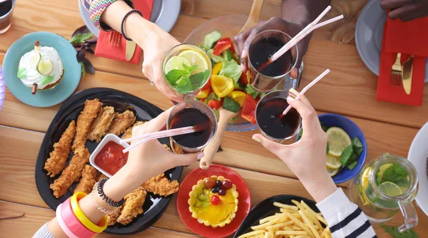 Draufsicht auf eine Gruppe von Menschen beim gemeinsamen Abendessen, während sie am Holztisch sitzen. Essen auf dem Tisch. Menschen essen Fast Food. — Stockfoto