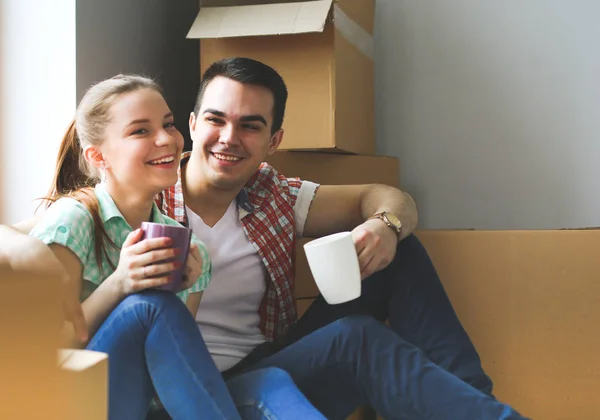 Couple moving in house sitting on the floor. Couple