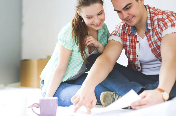 Pareja joven sentada en el suelo y calculando sobre sus ahorros. Pareja joven —  Fotos de Stock