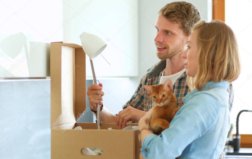 Young couple carrying big cardboard box at new home.Moving house