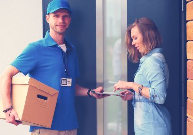 Mavi üniformalı gülümseyen kurye servis konseptine paket kutusu teslim eden teslimatçı. Mavi üniformalı gülümseyen teslimatçı.