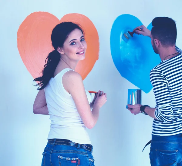 Retrato de feliz sorrindo jovem casal pintura parede interior da nova casa — Fotografia de Stock