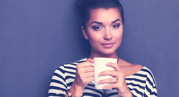 Young woman standing with cup, isolated on gray background. Young woman — Stock Photo, Image