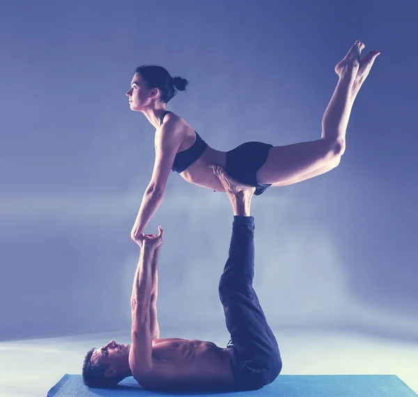 Pareja joven practicando acro yoga en estera en estudio juntos. Acroyoga. Un par de yoga. Socio yoga . — Foto de Stock