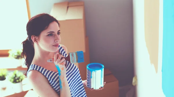 Gelukkig glimlachende vrouw schilderen interieur muur van nieuw huis — Stockfoto