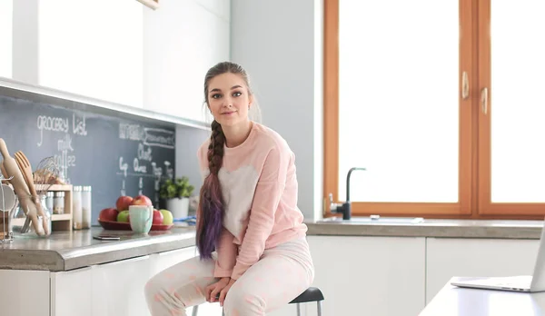 Jeune femme assise sur la table dans la cuisine . — Photo