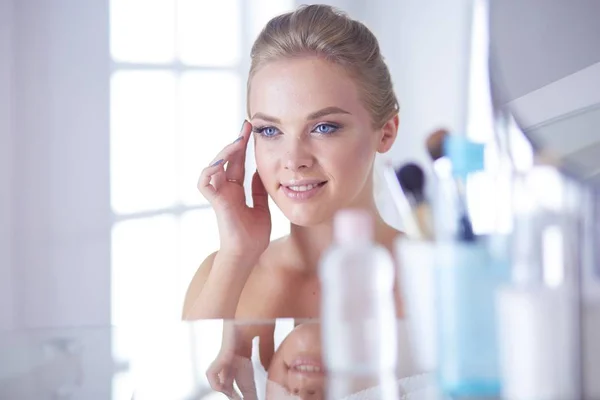 Jonge vrouw in badjas op zoek in badkamer spiegel — Stockfoto