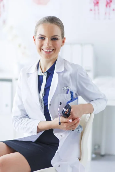 Retrato de una joven doctora sentada en el escritorio del hospital —  Fotos de Stock