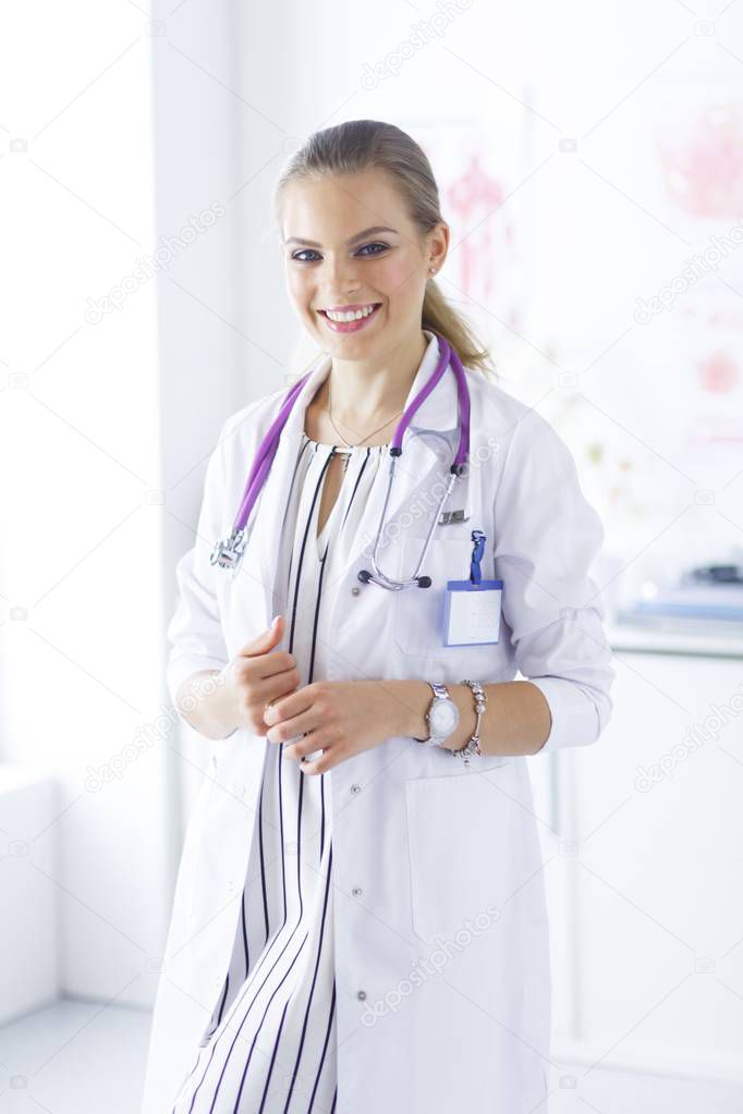 Smiling female doctor with a medical stethoscope in uniform standing