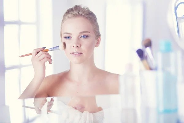 A picture of a young woman applying face powder in the bathroom — Stock Photo, Image