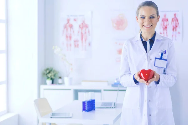 A doctor with stethoscope examining red heart, isolated on white background — Stock Photo, Image