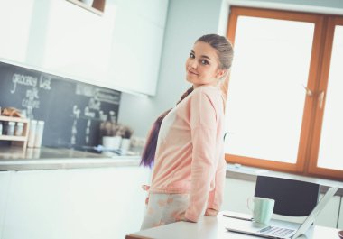 Cep telefonu ayakta modern mutfak kullanan kadın