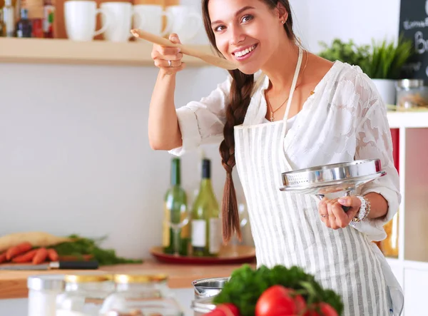 Cooking woman in kitchen with wooden spoon