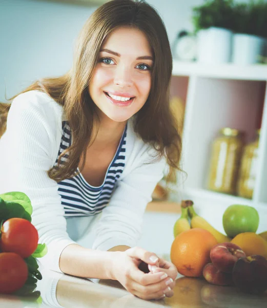 Jonge vrouw zit in de buurt van bureau in de keuken — Stockfoto