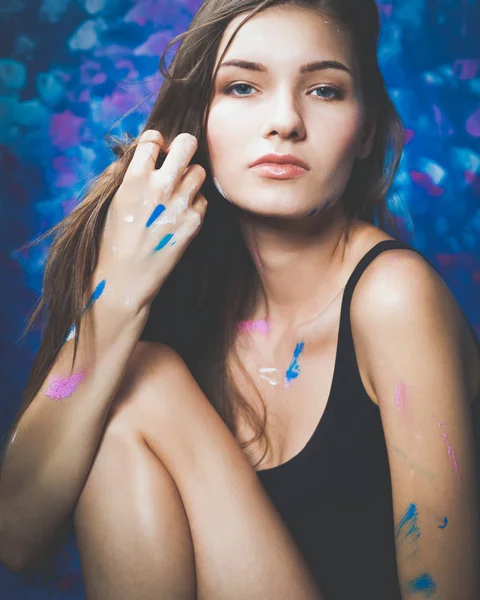 Mujer joven sentada cerca de la pared de pintura — Foto de Stock