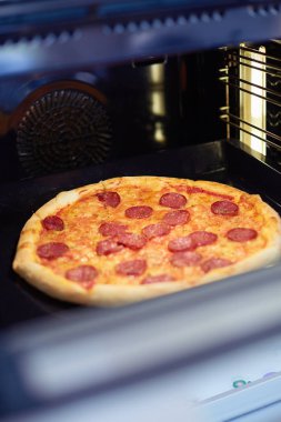 Mutlu genç bayan evde pizza pişiriyor.