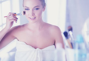 Genç bir kadının banyoya yüz pudrası sürerken fotoğrafı.