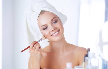 Genç bir kadının banyoya yüz pudrası sürerken fotoğrafı.