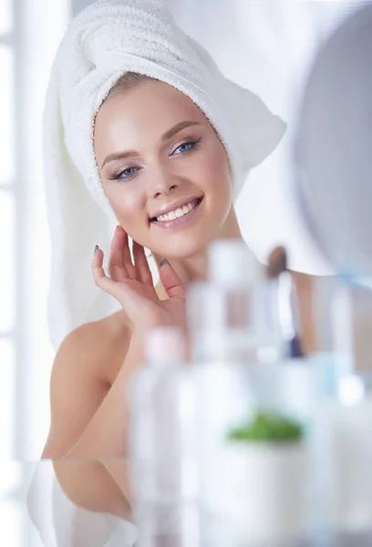 Young woman in bathrobe looking in bathroom mirror — Stock Photo, Image