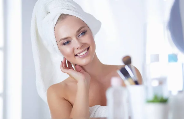 Young woman in bathrobe looking in bathroom mirror — Stock Photo, Image