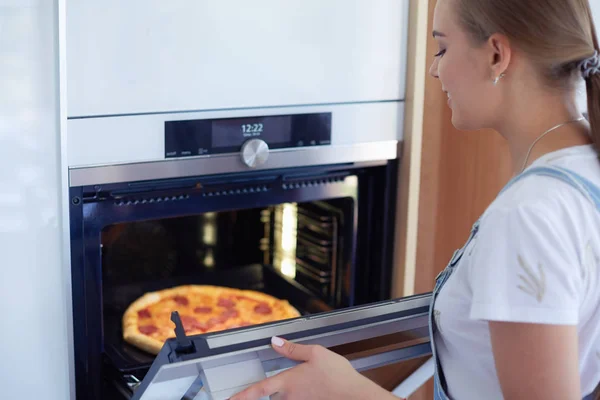 Šťastná mladá žena vaří pizzu doma — Stock fotografie