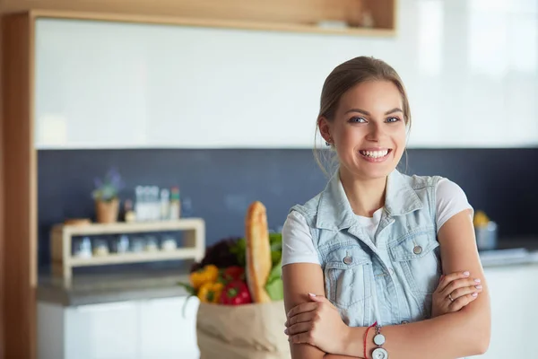 Porträtt av ung kvinna står med armarna korsade mot kök bakgrund — Stockfoto