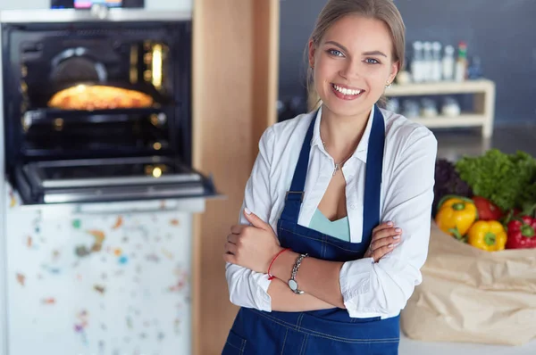 Portrait de jeune femme debout avec les bras croisés sur fond de cuisine — Photo