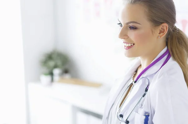 Médica sorridente com estetoscópio médico de pé uniforme — Fotografia de Stock