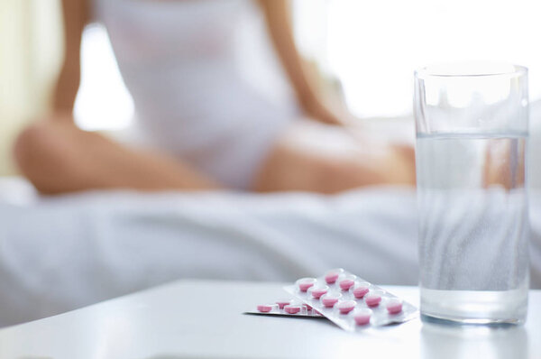 Молодая красивая женщина с таблетками лежал на кровати в спальне
