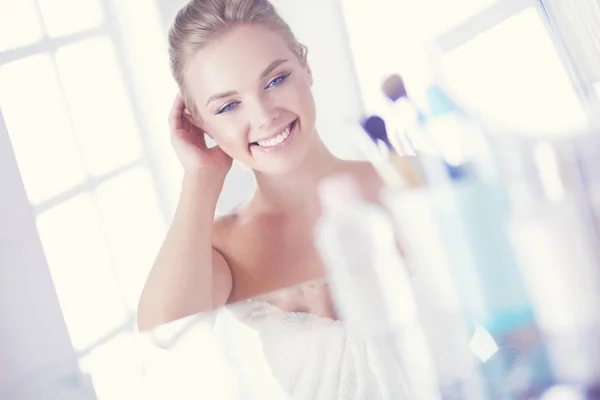 Jonge vrouw in badjas op zoek in badkamer spiegel — Stockfoto