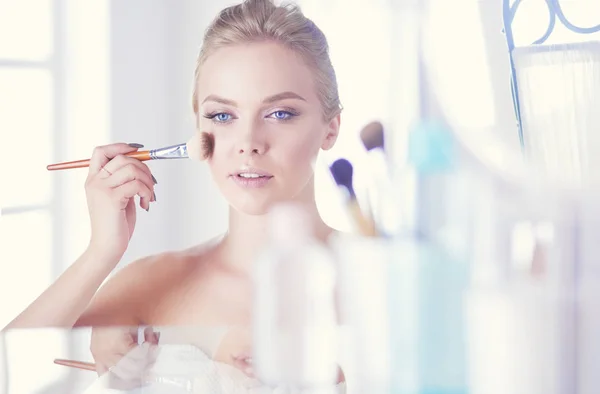 Uma foto de uma jovem mulher aplicando pó facial no banheiro — Fotografia de Stock