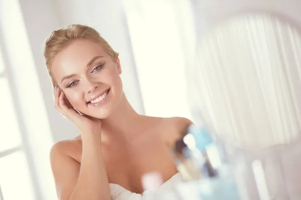 Jonge vrouw in badjas op zoek in badkamer spiegel — Stockfoto