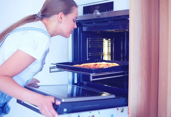 Šťastná mladá žena vaří pizzu doma — Stock fotografie