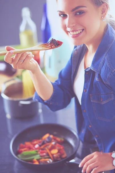 Young woman cooking healthy food holding a pan with vegetables is it. Healthy lifestyle, cooking at home concept