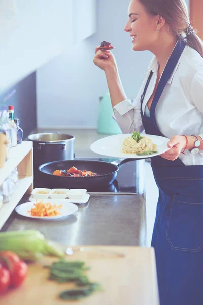 Junge Frau steht am Herd in der Küche — Stockfoto