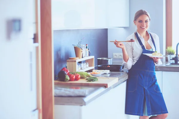 Mujer joven parada junto a la estufa en la cocina —  Fotos de Stock
