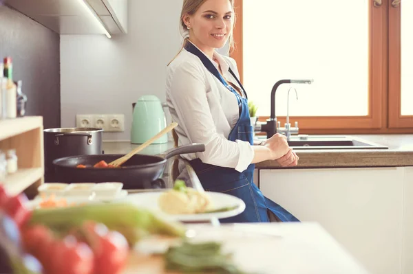 Jeune femme debout près de la cuisinière dans la cuisine — Photo