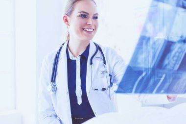 Genç ve çekici bayan doktor röntgen görüntülerine bakıyor.