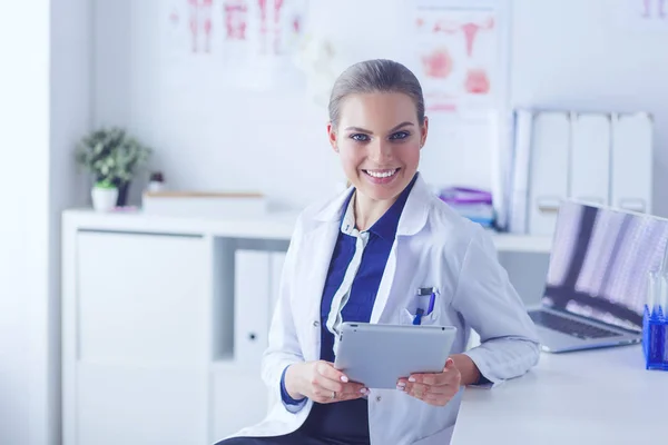 Πορτρέτο της γυναίκας γιατρού στο διάδρομο του νοσοκομείου, κρατώντας tablet υπολογιστή, κοιτάζοντας κάμερα, χαμογελώντας — Φωτογραφία Αρχείου