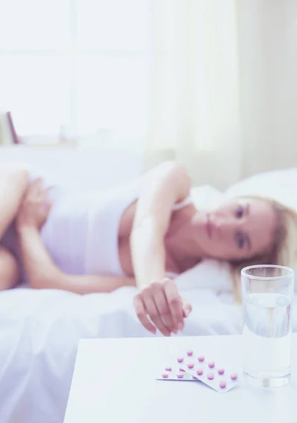 Joven hermosa mujer con pastillas tumbado en la cama en el dormitorio — Foto de Stock